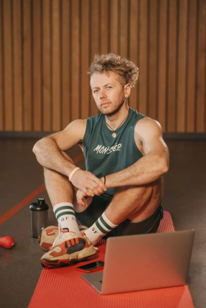 Mann sitzt nach dem Training im Studio auf der Matte